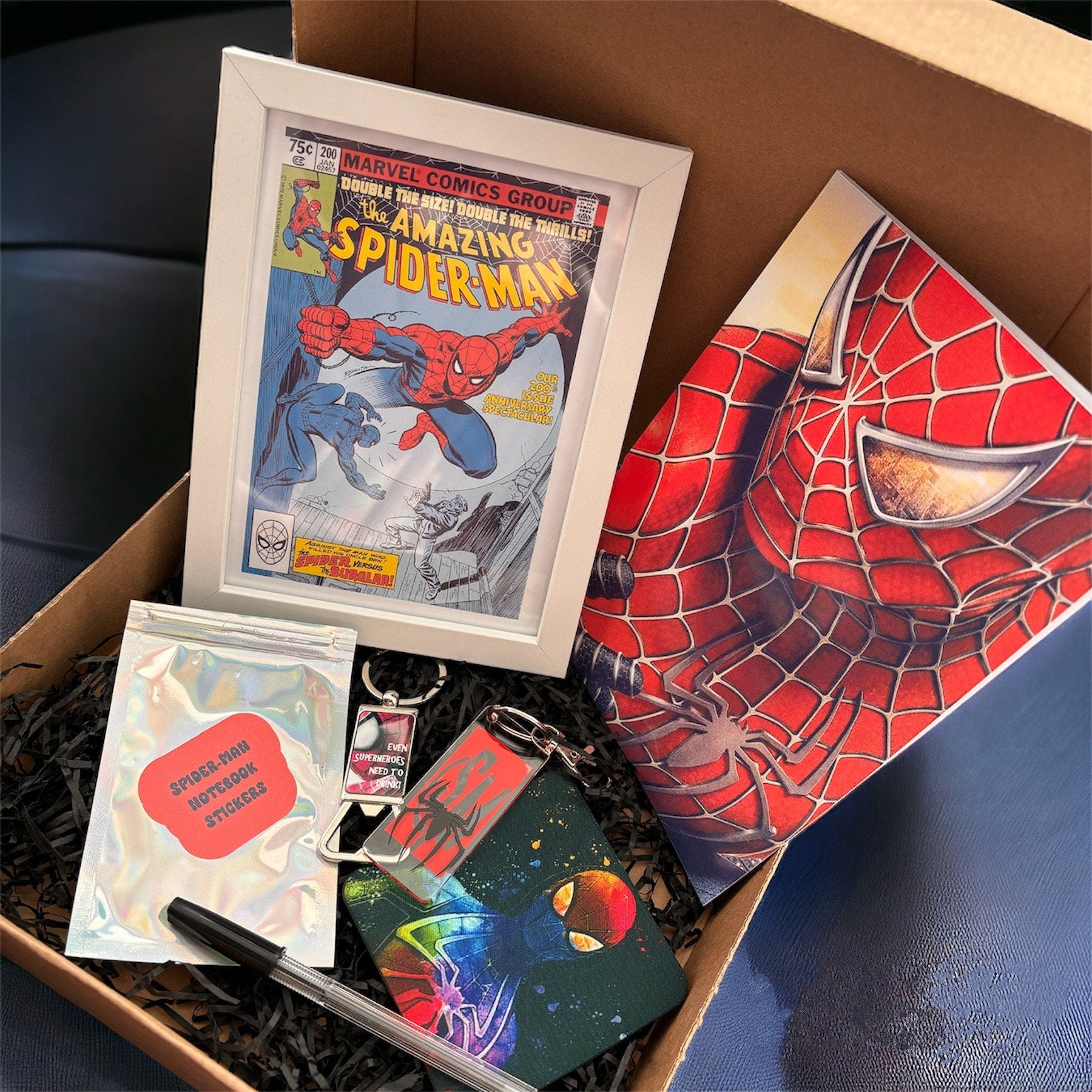 Hand-Made Spider-Man Gift Set - Exclusive 5x7 Foil Print, Notebook, and More!  Our Spider-Man Gift Set is a sensational collection celebrating everyone's favorite wall-crawler! Dive into the superhero universe with a framed 5x7 high-gloss foil print of The Amazing Spider-Man comic cover, accompanied by a range of themed accessories.